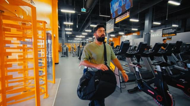 Gym workout man with sports bag at fitness center, modern gym equipment, cardio machines, healthy lifestyle, fitness training, exercise workout, health and wellness, gym facility, active living, athletic training.