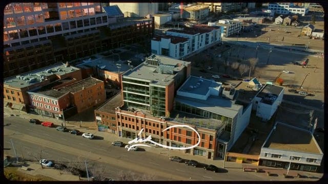 Aerial view of downtown urban area with modern buildings, streets, and parked cars, showcasing commercial and residential architecture in a vibrant cityscape.