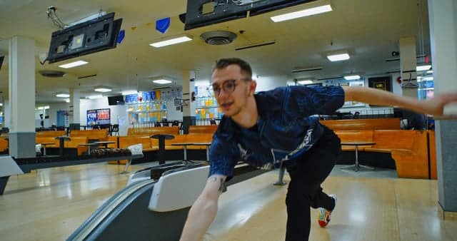 A young man bowling at an indoor bowling alley, demonstrating fun and leisure activities in a vibrant entertainment setting.