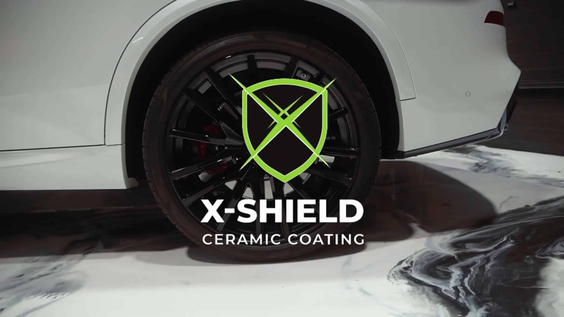 Ultra-modern white car wheel with black rim and red brake caliper showcasing X-Shield ceramic coating technology.