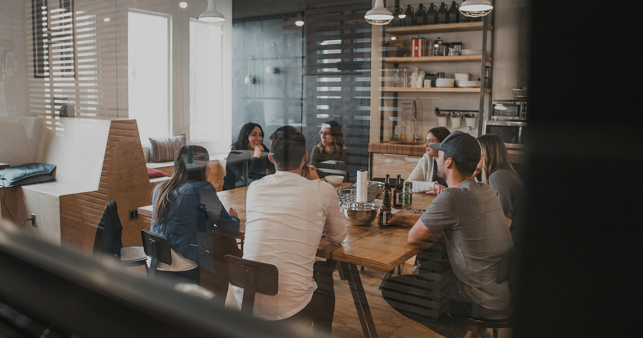 Group of diverse professionals having a business meeting in a modern conference room with natural light and wooden decor.