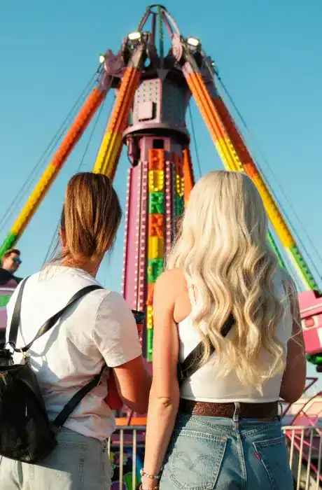 Two women enjoying a colorful amusement park ride at Q Filmz Media, capturing fun and entertainment in a vibrant setting.