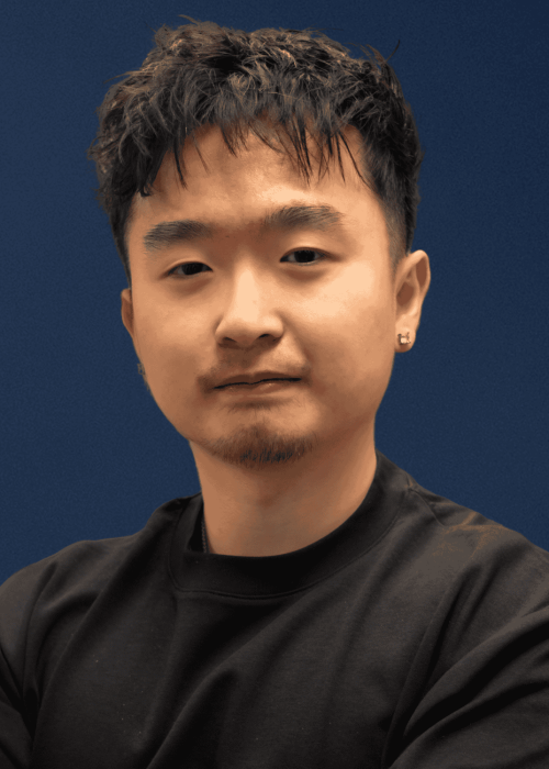 Young Asian man with short dark hair, beard, and earrings, wearing a black shirt against a blue background, representing modern cinephile or digital media influencer.